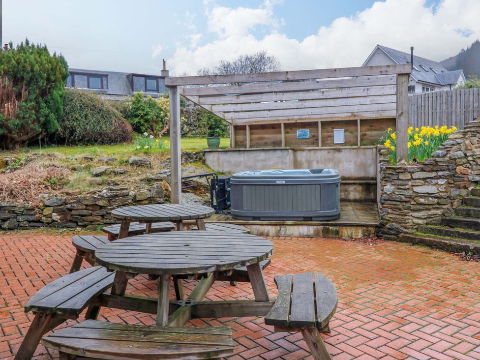 An outdoor patio with a hot tub and wooden furniture at Tayview in Killin