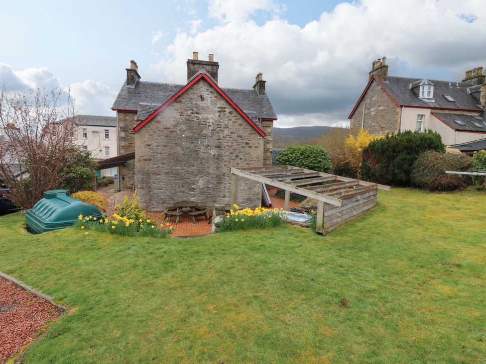 A garden with a stone house and furniture at Tayview in Killin