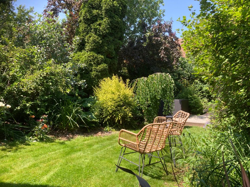 A garden with grass and chairs at Gingerbread Cottage in Canterbury