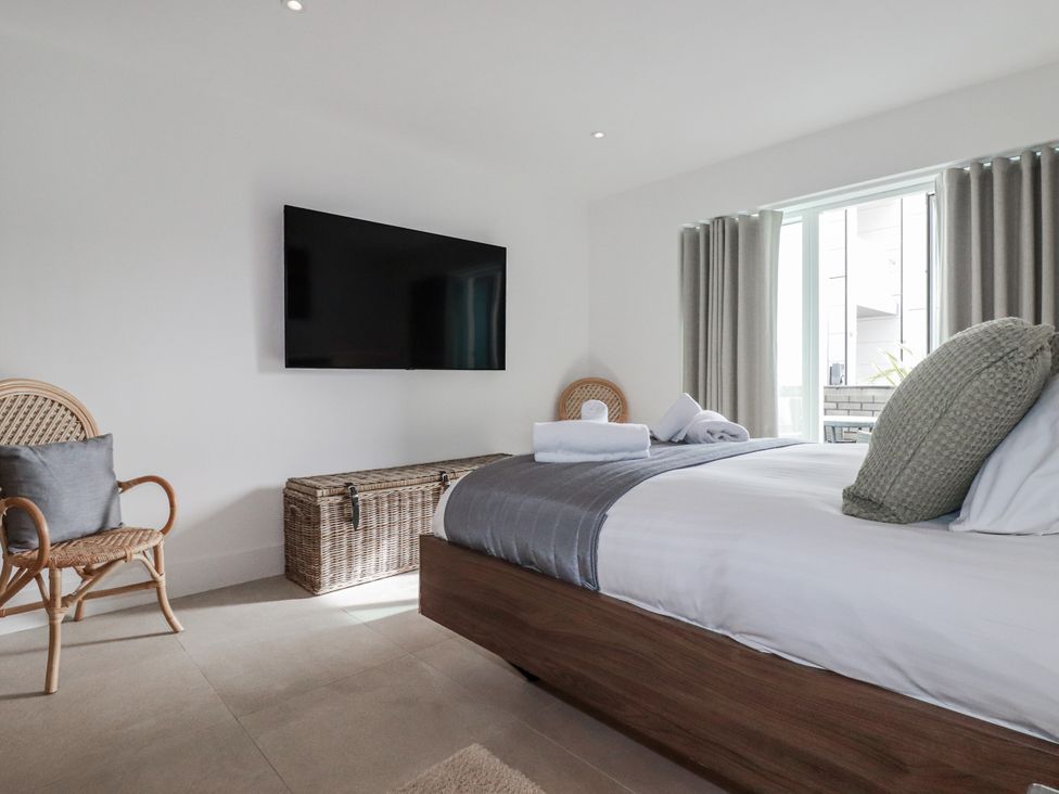 A bedroom with a bed, chair, and television at 13 Cliff Edge in Newquay