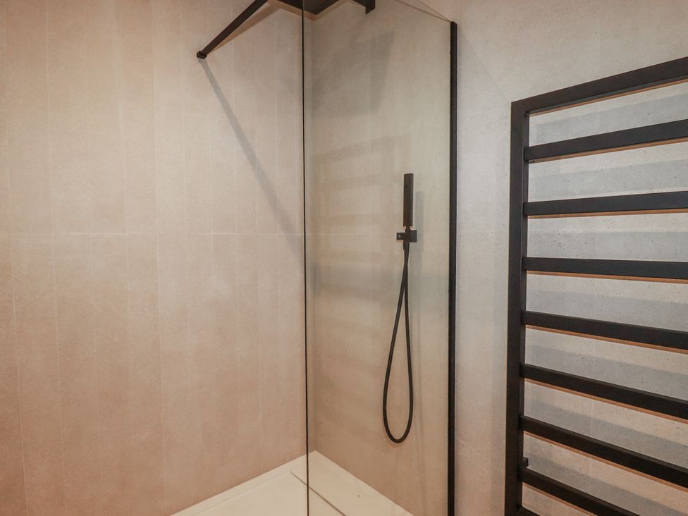 A shower with glass panel and towel radiator at 13 Cliff Edge in Newquay