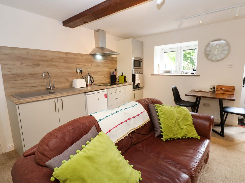 A kitchen with a sofa and dining table at La'l Skaithe Soulby near Kirkby Stephen