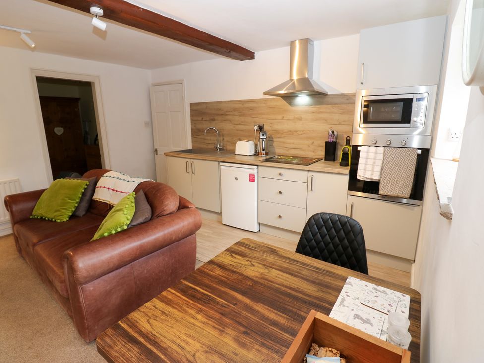 A kitchen with a sofa and dining area at La'l Skaithe in Soulby near Kirkby Stephen