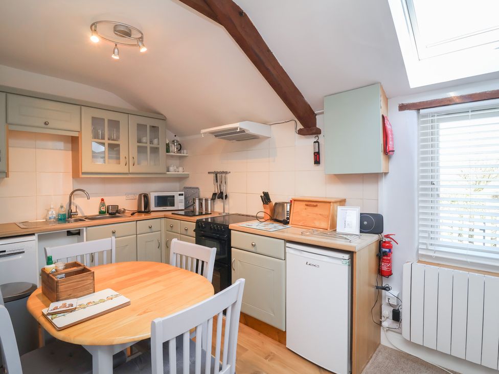 A kitchen with appliances and dining table at Ash Cottage in Combe Martin