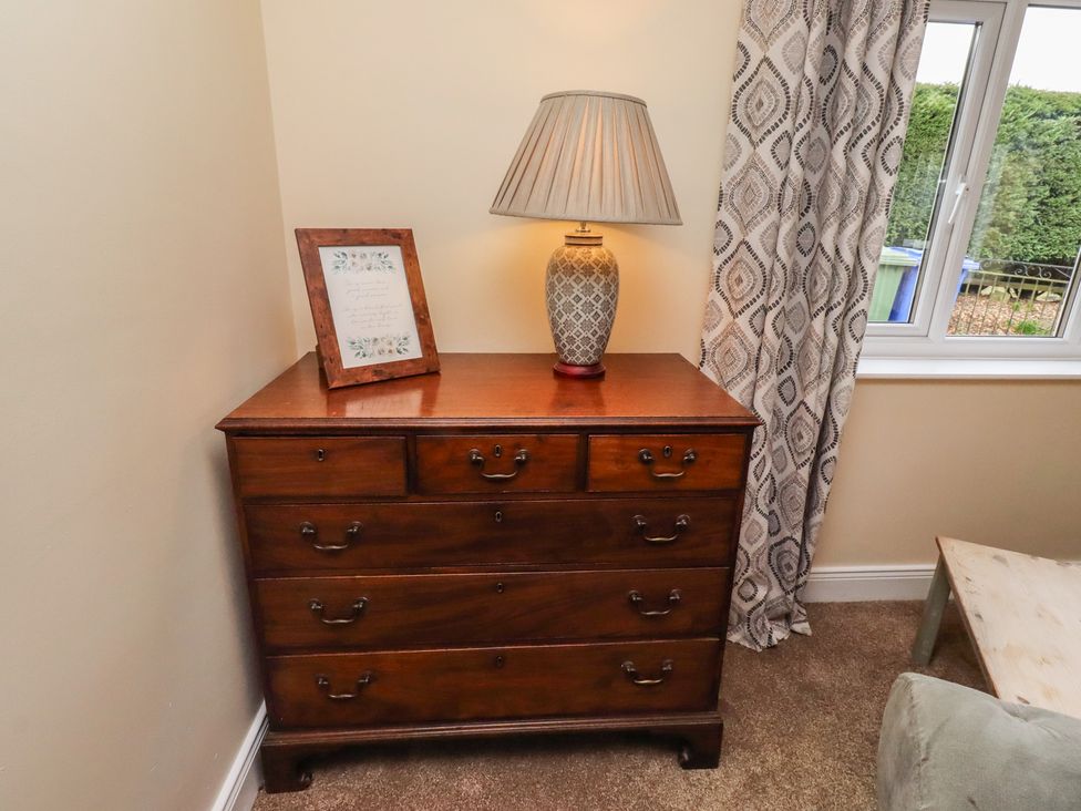 A living room with a wooden dresser and a lamp at Whinney Moor in Alnwick