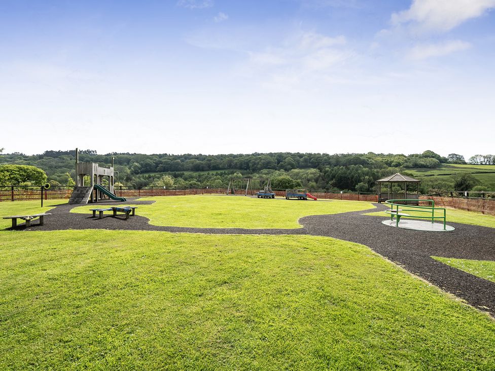 An outdoor playground with a slide and swings at Harcombe House Accessible Pet Friendly Bungalow in Chudleigh