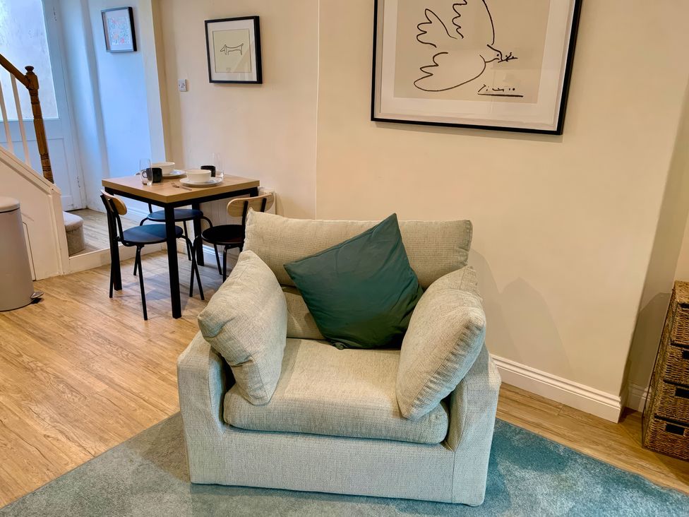 A living room with an armchair and a dining table at Bobbin Cottage in Swanage