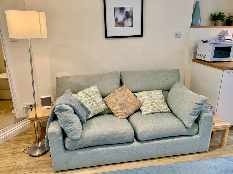 A living room with a sofa and lamp at Bobbin Cottage in Swanage