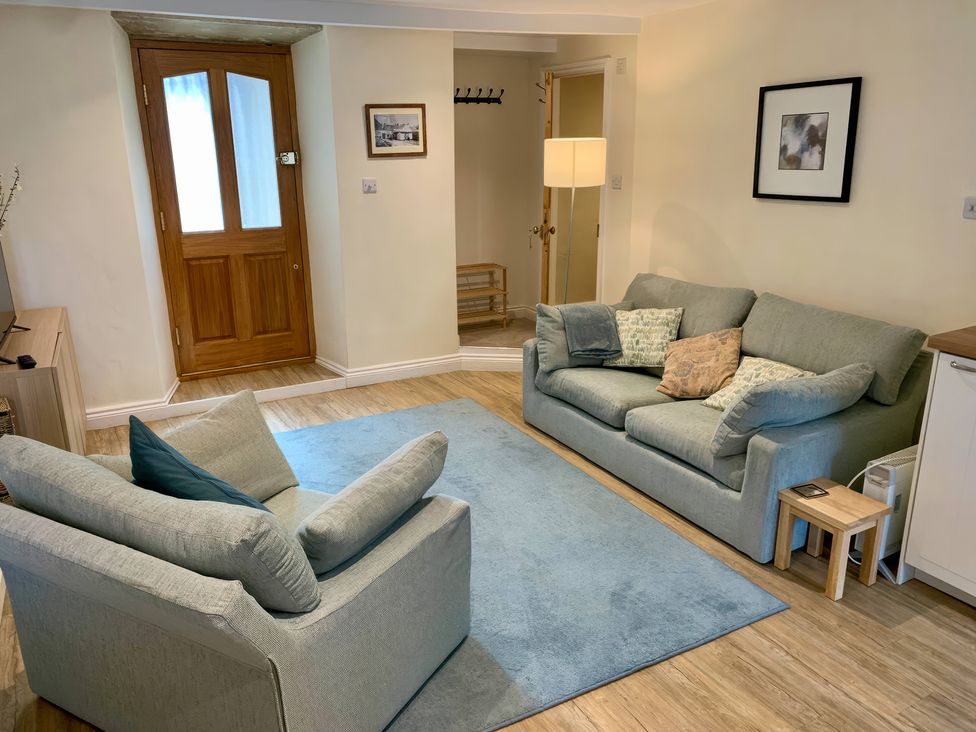 A living room with sofas and a rug at Bobbin Cottage in Swanage