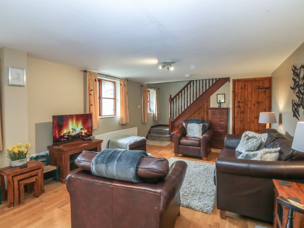 A living room with sofas and a fireplace at Beudy Penarddwnion Rhydymain near Dolgellau