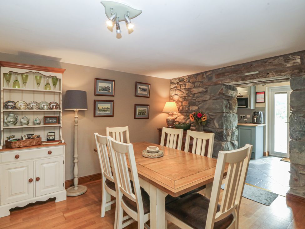 A dining room with a wooden table and chairs at Beudy Penarddwnion Rhydymain near Dolgellau
