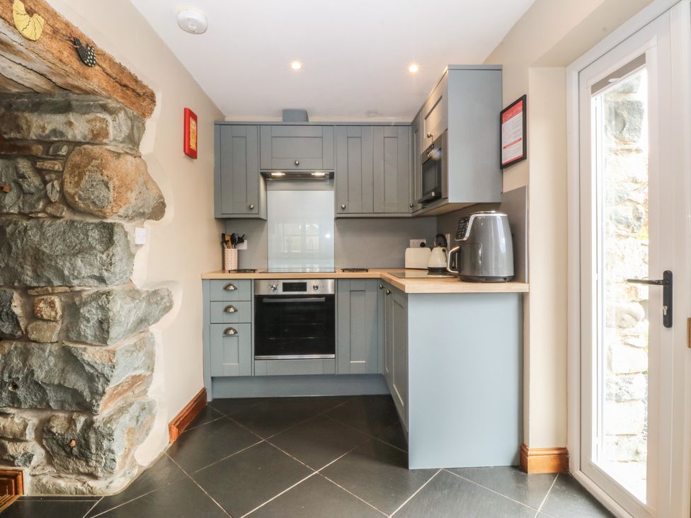 A kitchen featuring a stone wall and modern appliances at Beudy Penarddwnion Rhydymain near Dolgellau