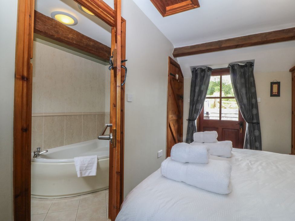 A bedroom with a bathtub visible through the doorway at Beudy Penarddwnion in Rhydymain near Dolgellau