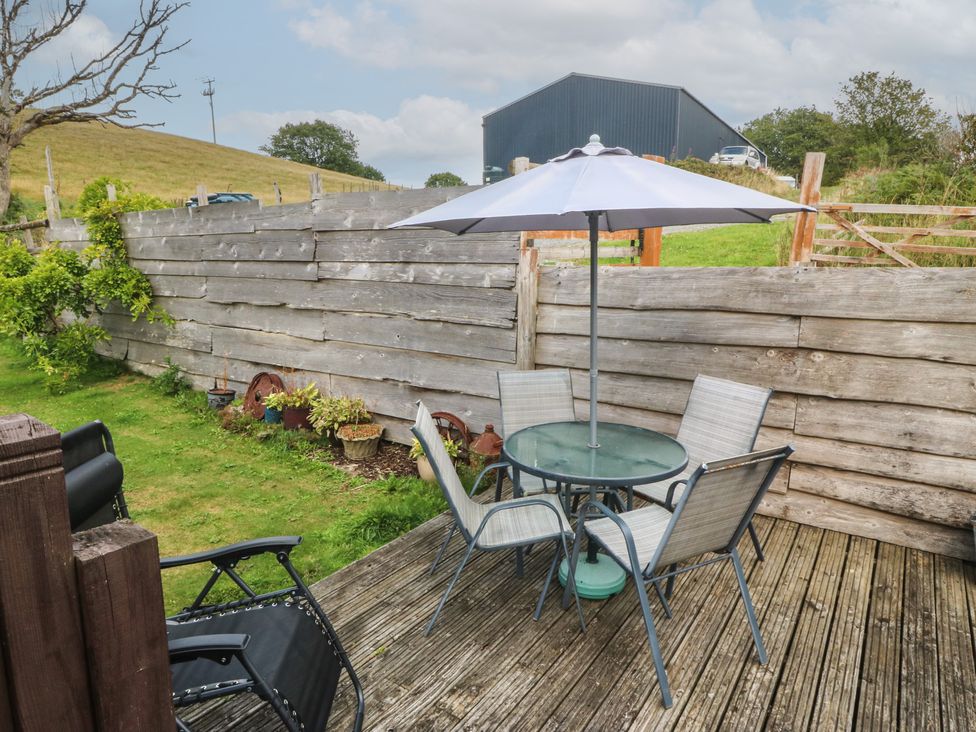 A garden with a table and chairs under an umbrella at Beudy Penarddwnion Rhydymain near Dolgellau