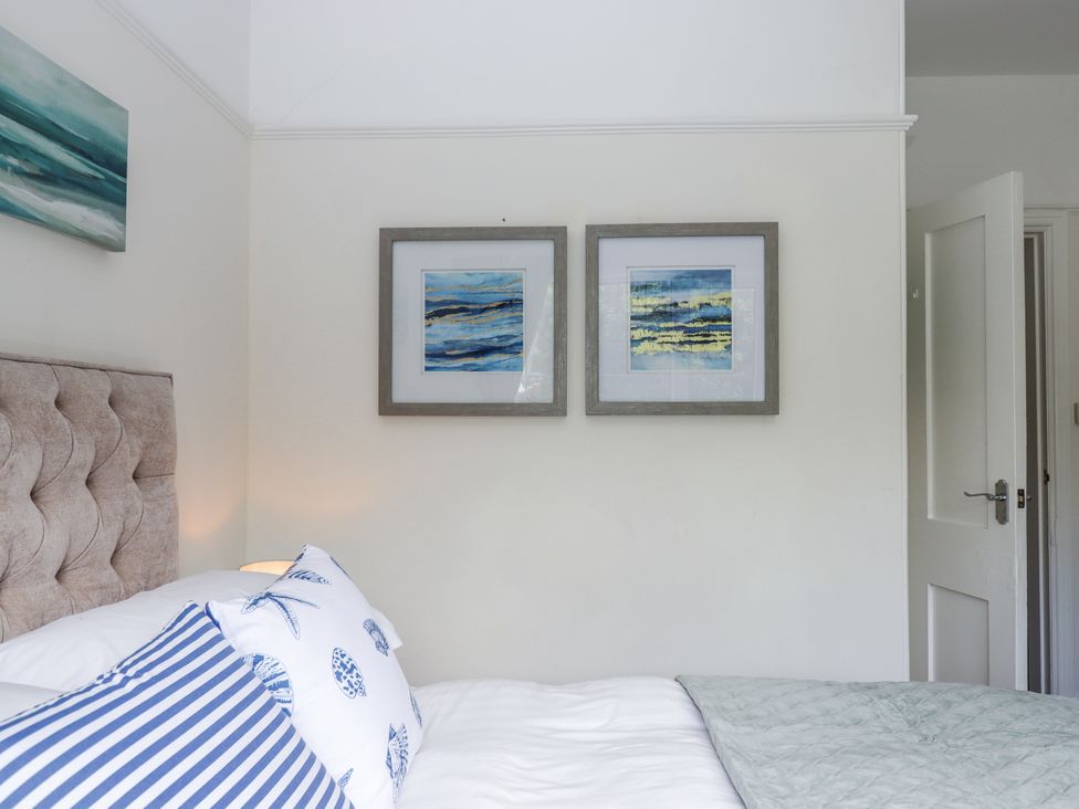 A bedroom with a bed and paintings on the wall at Kinbrae Apartment in Torquay
