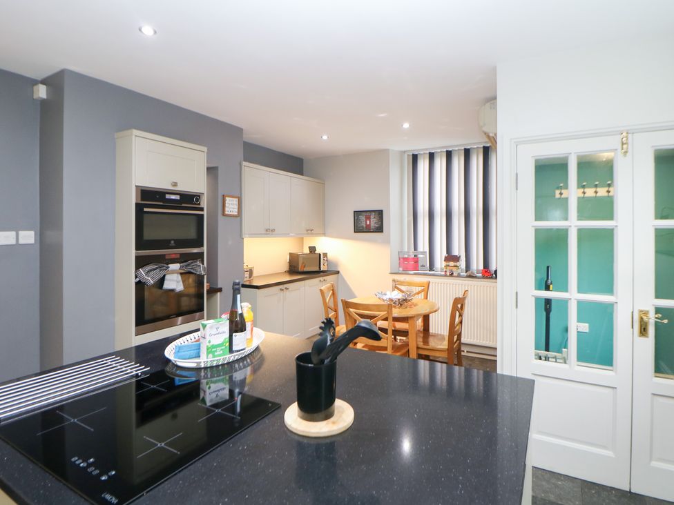 A kitchen with appliances and dining furniture at The Old Post Office in Wirksworth