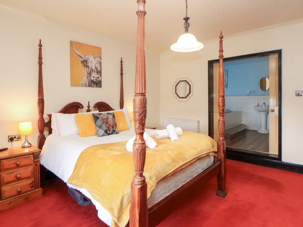 A bedroom with a four-poster bed and a bathroom doorway at The Old Post Office in Wirksworth