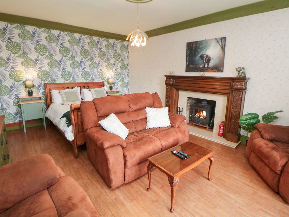 A living room with a sofa, armchair, coffee table, and fireplace at The Old Post Office in Wirksworth