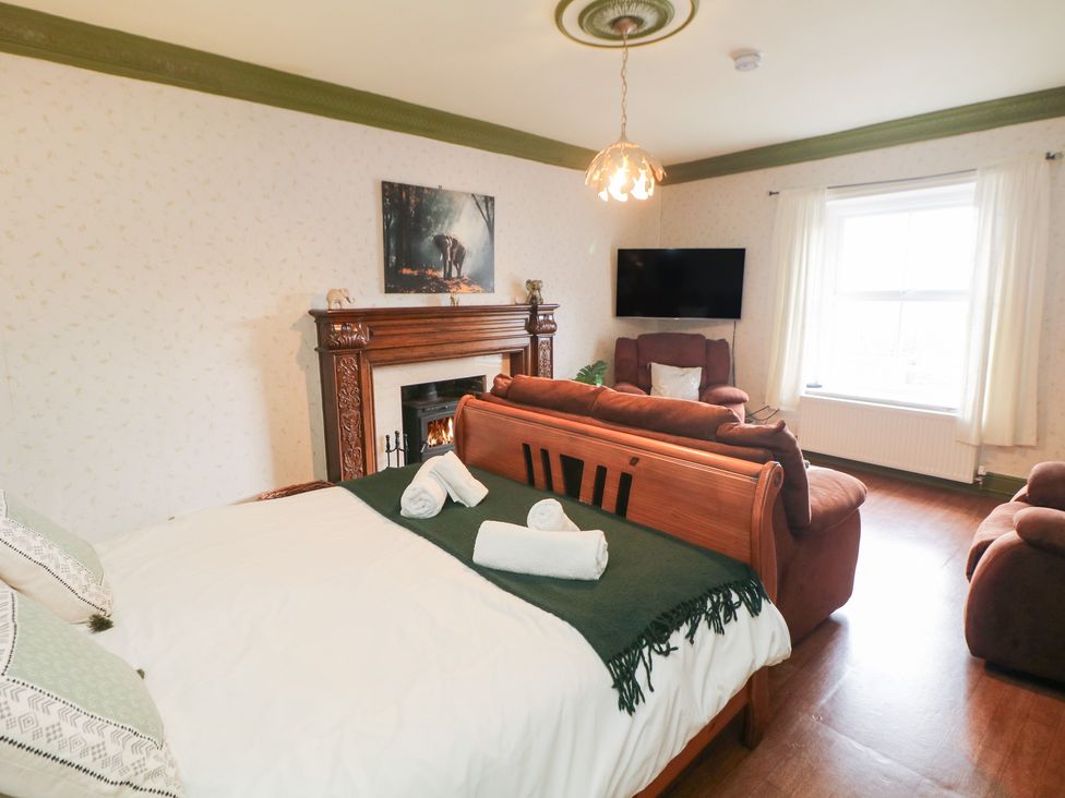 A bedroom with a bed, sofa, and fireplace at The Old Post Office Wirksworth