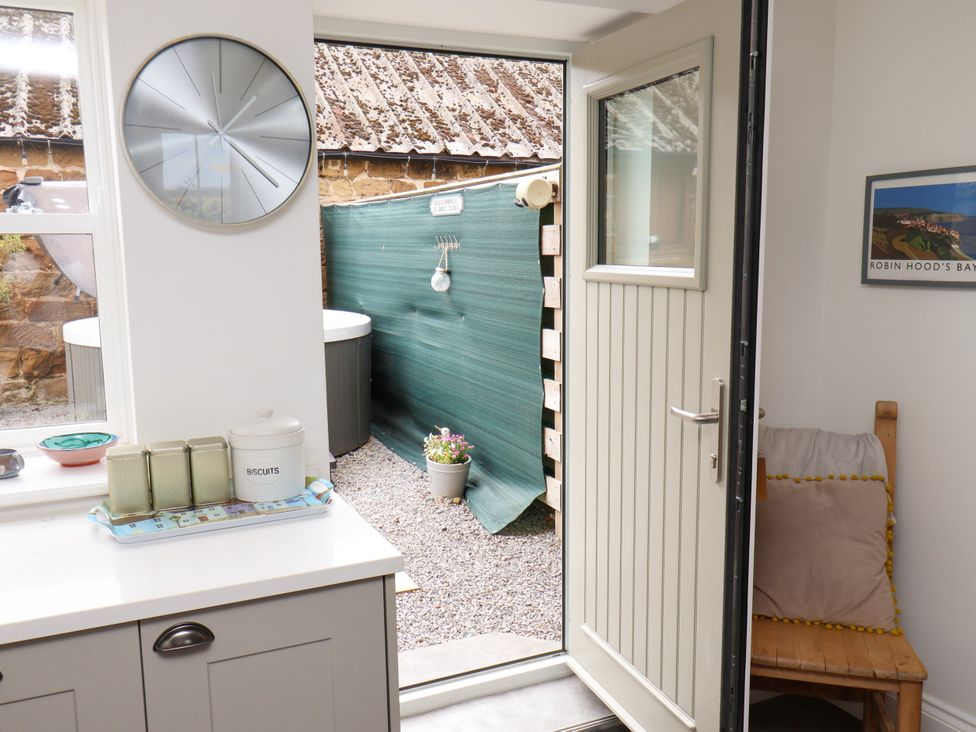 A kitchen with an open door leading to a garden area at Fell Briggs Cottage in Marske-By-The-Sea