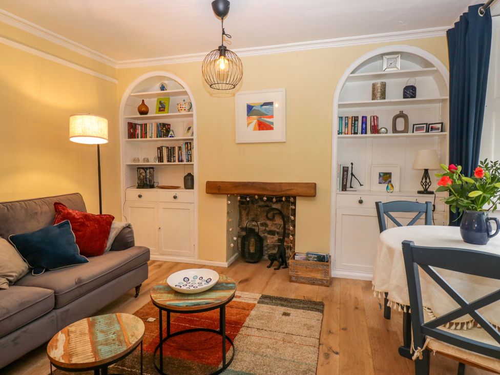 A living room with a sofa, bookshelves, and a dining table at 1 Tower House in Cartmel