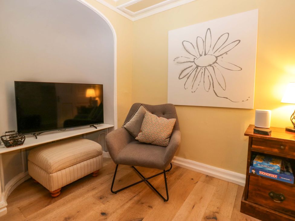 A living room with a television, chair, and table at 1 Tower House in Cartmel