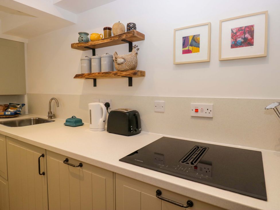 A kitchen featuring a sink, kettle, toaster, and shelf at 1 Tower House in Cartmel