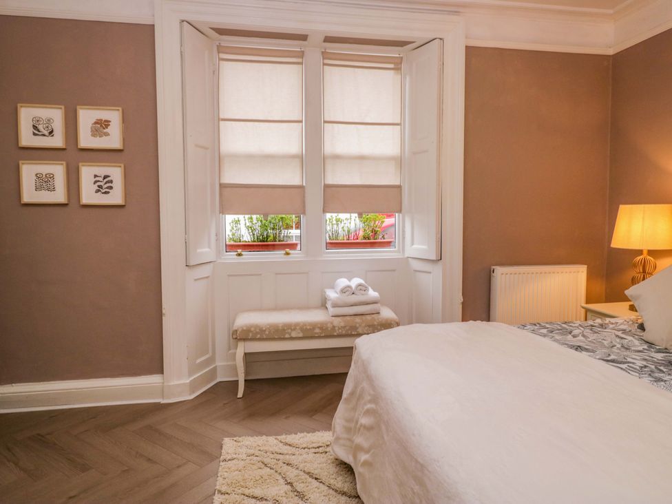 A bedroom with a bed, bench, and window at 1 Tower House in Cartmel