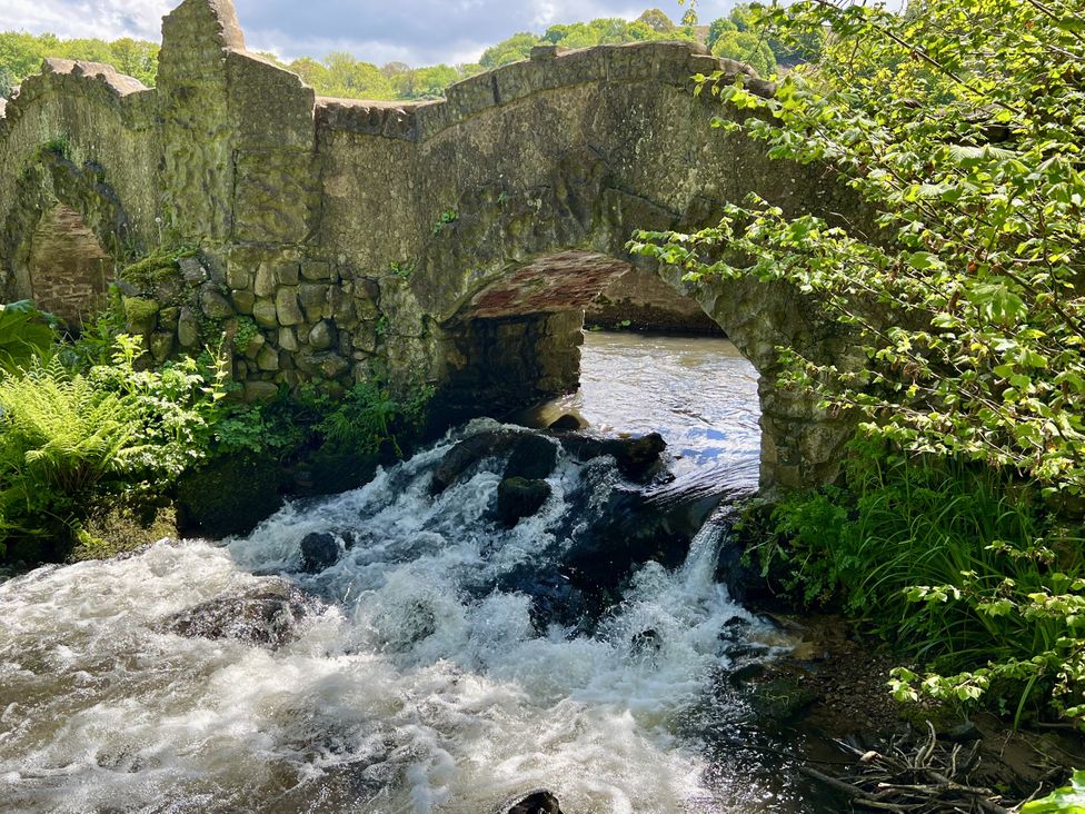 A bridge over a river with a stream flowing at Hazel Barn North Molton