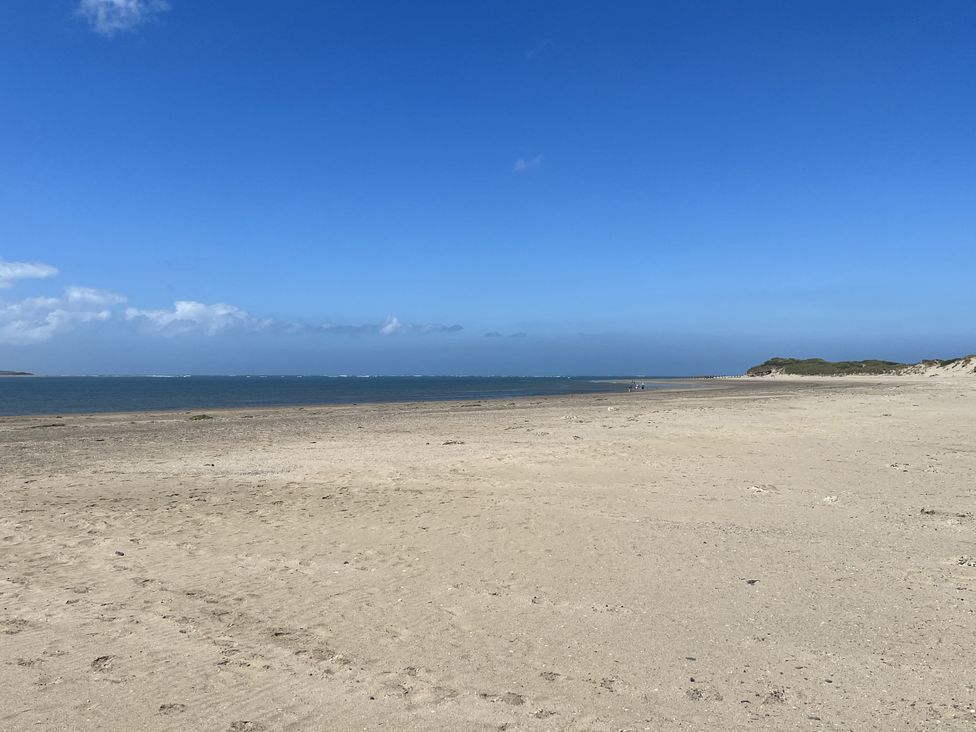 A beach with sand, water, and a clear sky at Hazel Barn in North Molton