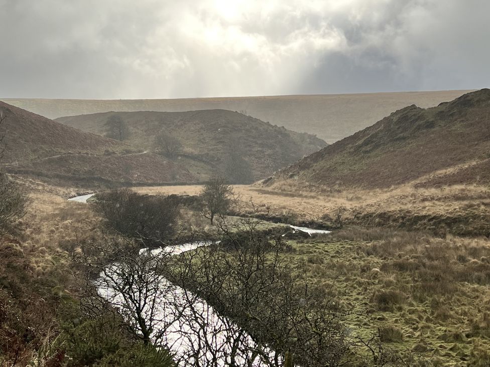 A river winding through hills and grasslands at Beechcroft Cottage in North Molton
