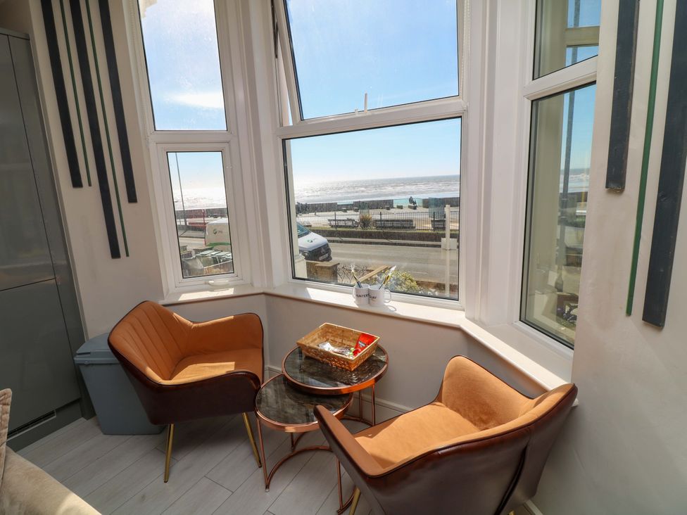 A sitting room with chairs and a table overlooking the ocean at Apt 4 @ Hunter's Quay in Bridlington