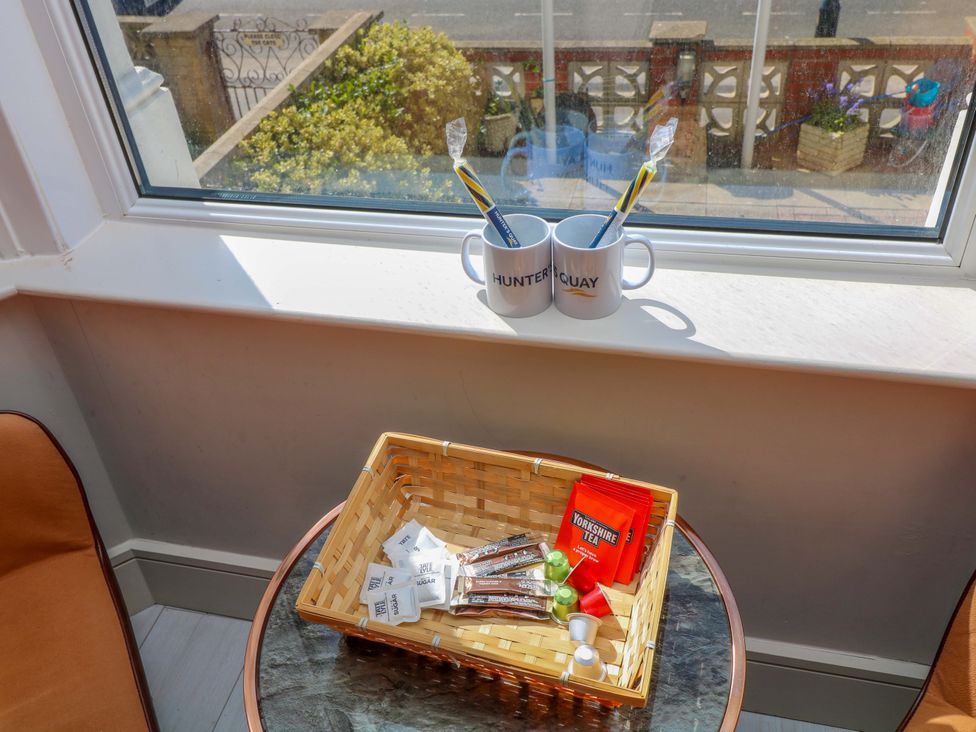 A kitchen window sill with mugs and a basket of tea supplies at Apt 4 @ Hunter's Quay in Bridlington