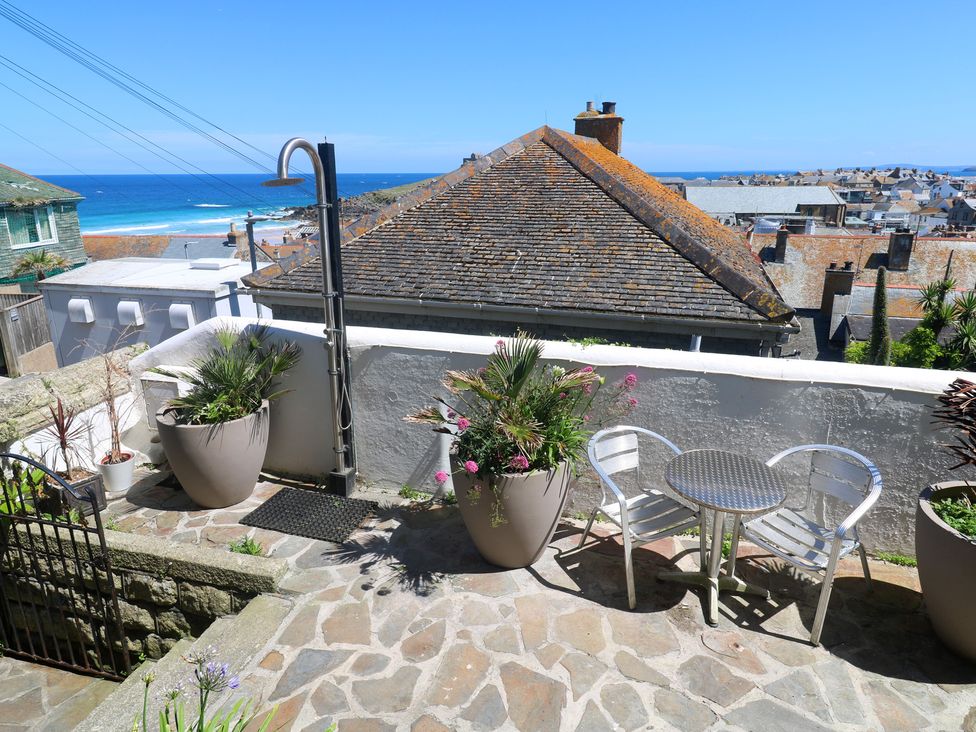 A terrace with a table and chairs overlooking the sea at Heron St Ives