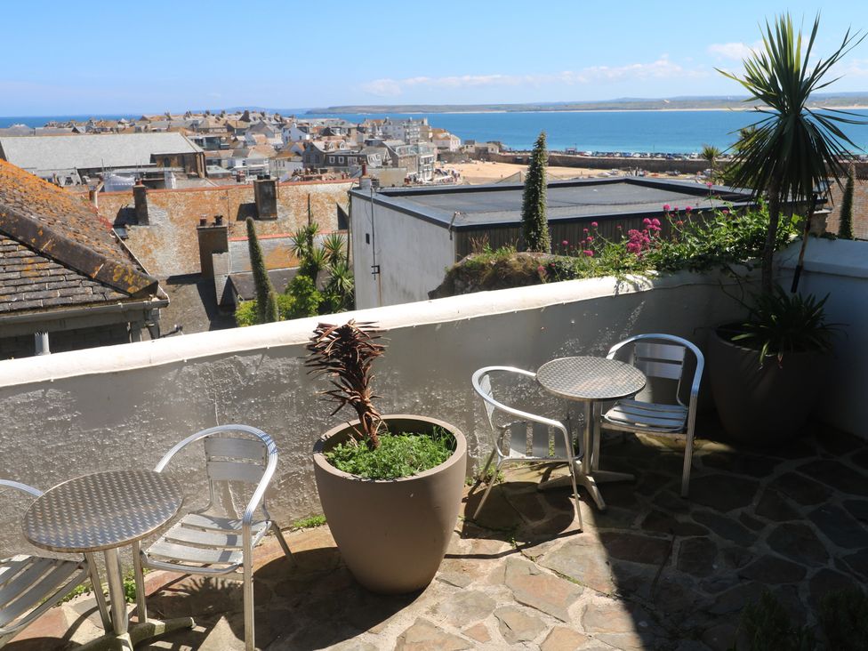 A terrace with tables and chairs overlooking the sea at Heron in St Ives