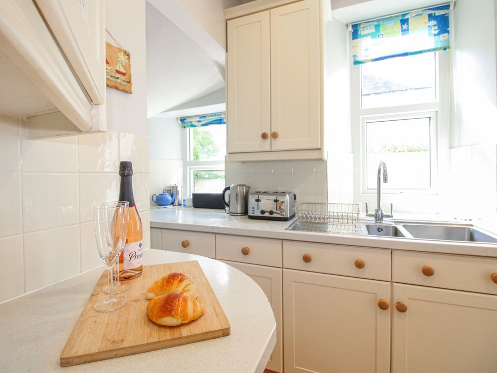 A kitchen with a croissant and champagne on a counter at Eddystone in Hope Cove