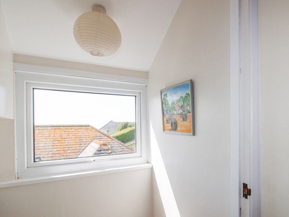 A hallway with a window, light fixture, and painting at Eddystone, Hope Cove