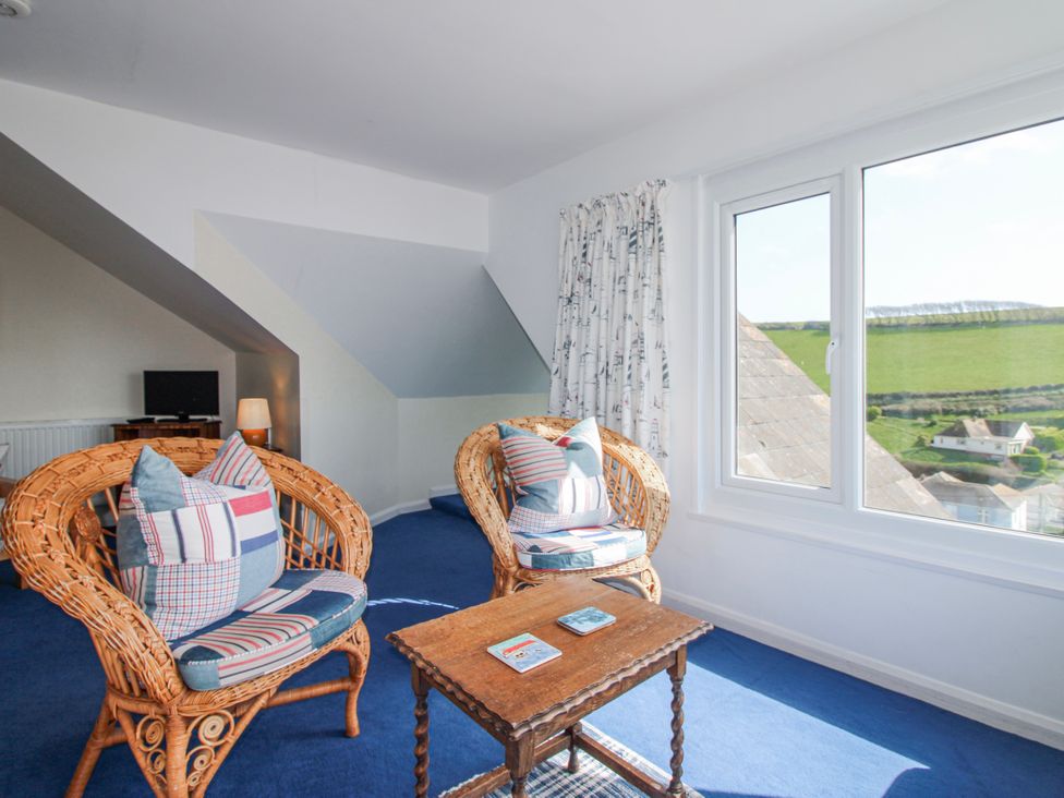 A living room with wicker chairs and a table at Eddystone in Hope Cove