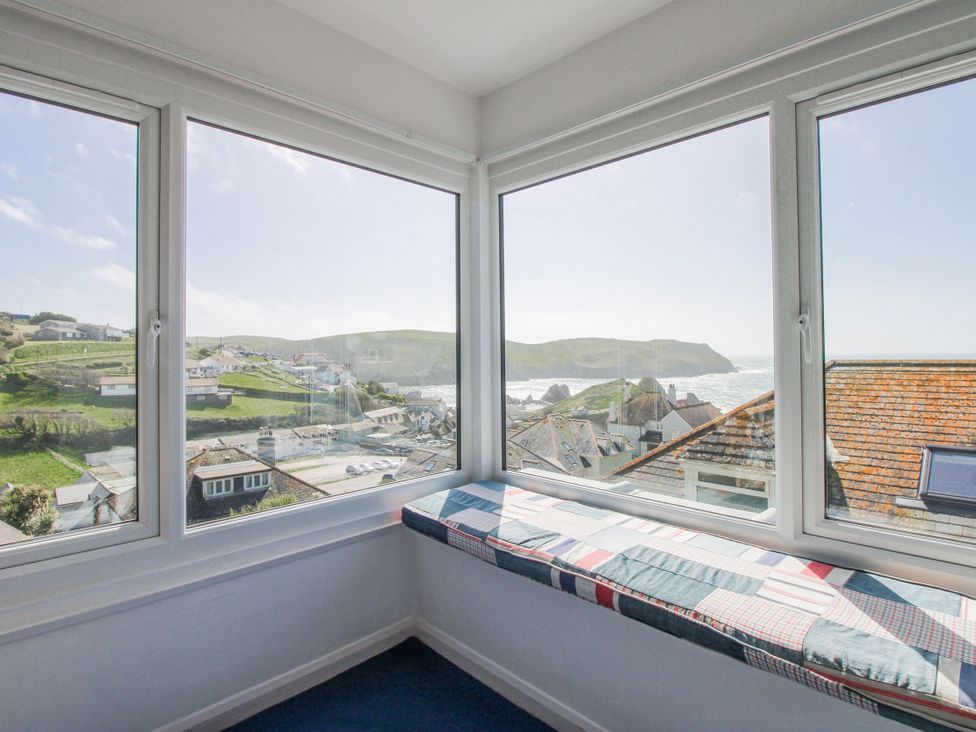 A sunroom with a window seat and views of the ocean at Eddystone Hope Cove