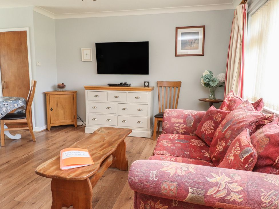 A living room with a television and a sofa at Bro Mebyd in Criccieth
