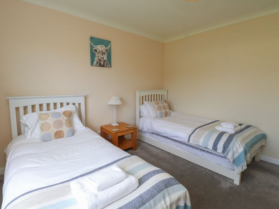 A bedroom with two beds and a nightstand at Bro Mebyd in Criccieth