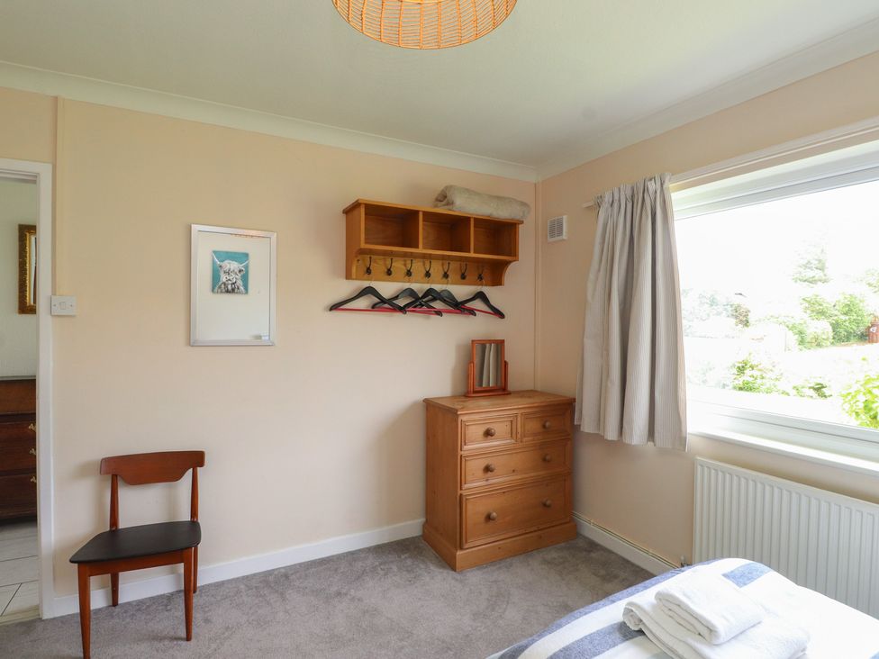 A bedroom with a chair and a chest of drawers at Bro Mebyd Criccieth