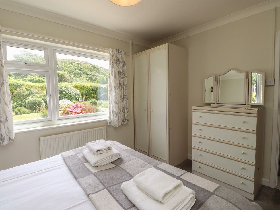 A bedroom with a bed, wardrobe, and dressing table at Bro Mebyd, Criccieth