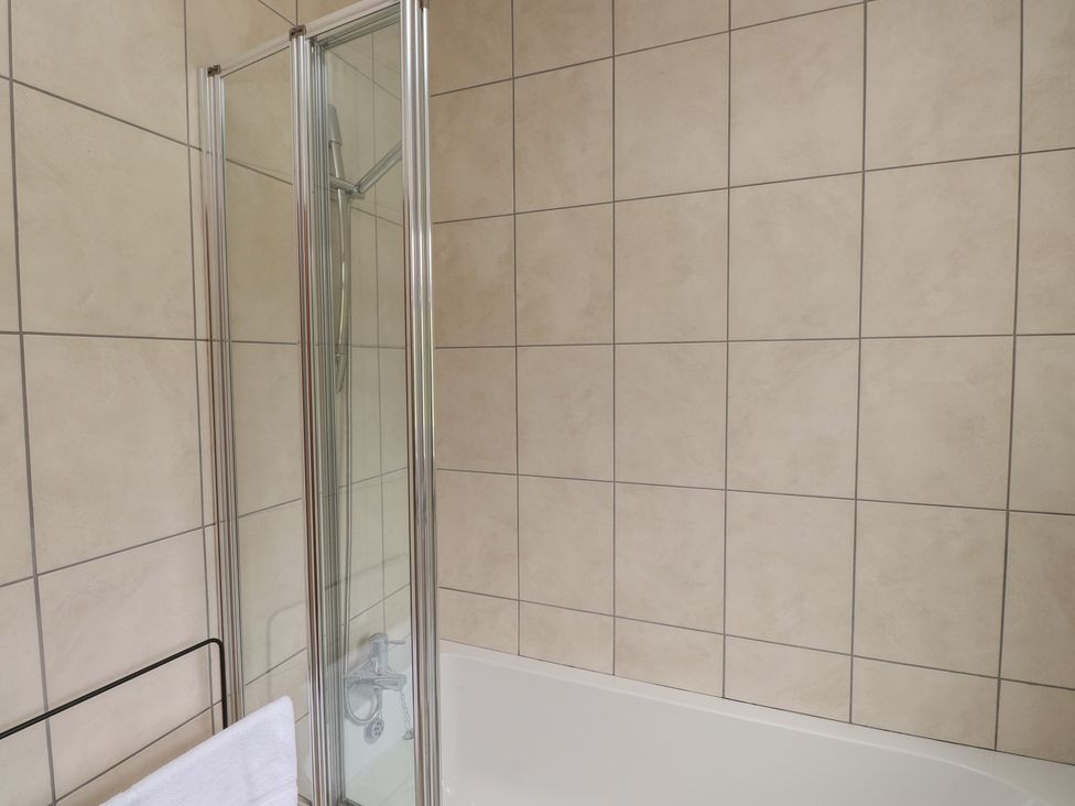 A bathroom with a shower and bathtub at Bro Mebyd in Criccieth