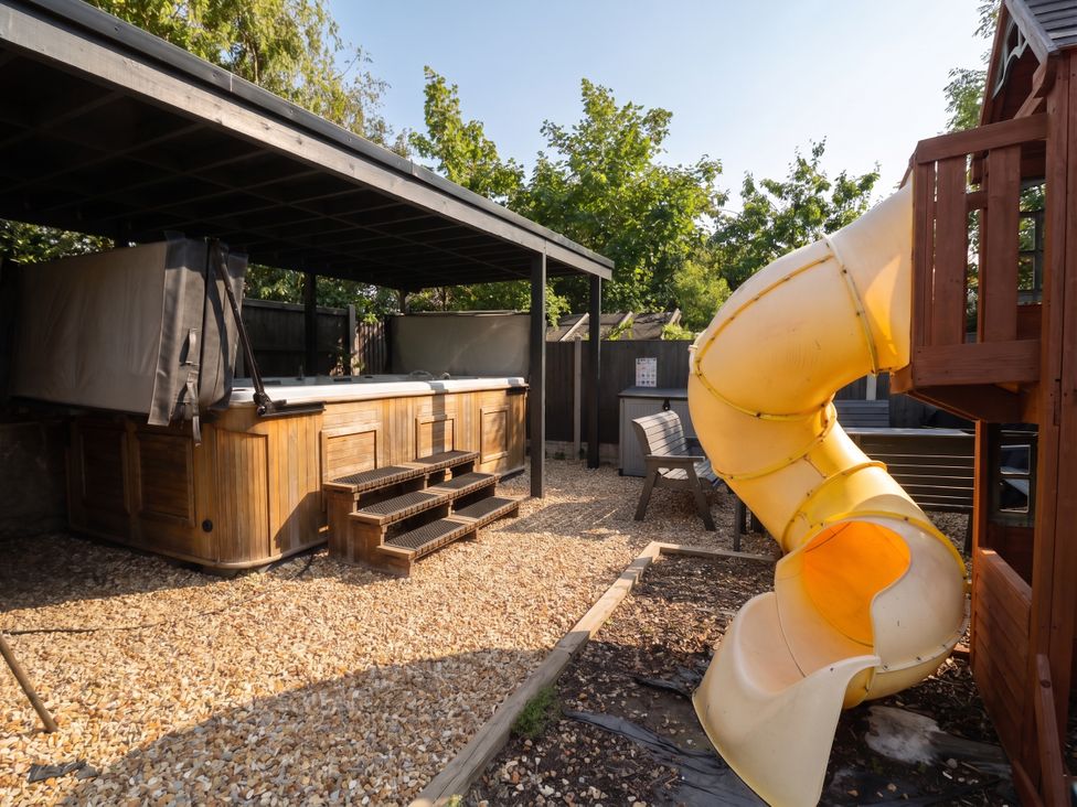An outdoor area with a hot tub, slide, and seating at Cabin Hill in Rhos-On-Sea