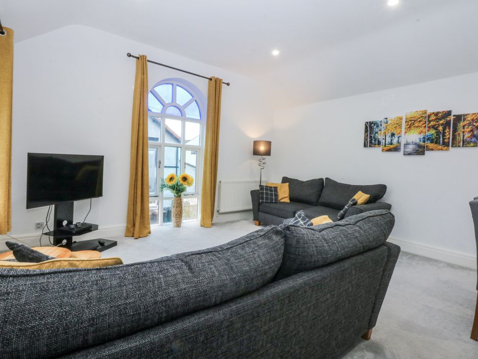A living room with a sofa and television at Capel Y Ffynnon in Bryan Pardew near Llandudno Junction