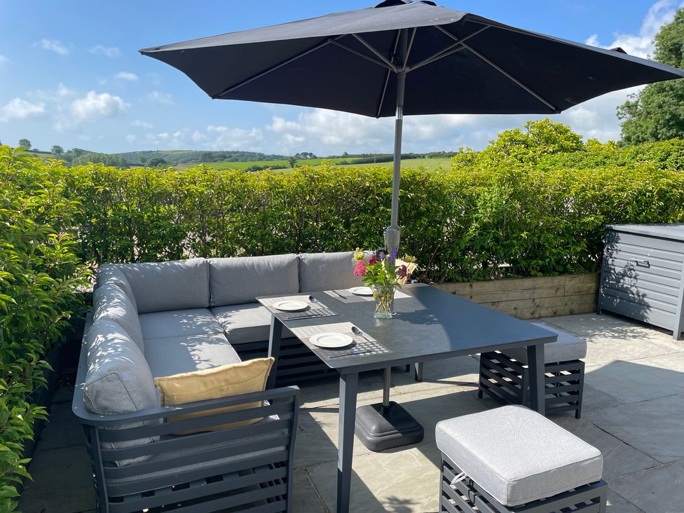 A garden seating area with a table and umbrella at 2 The Manor House, Hillfield Village, Dartmouth