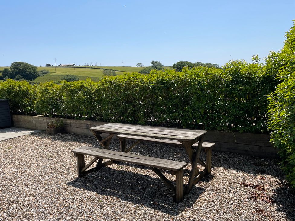 A table and bench surrounded by gravel in a garden at 2 The Manor House, Hillfield Village Dartmouth