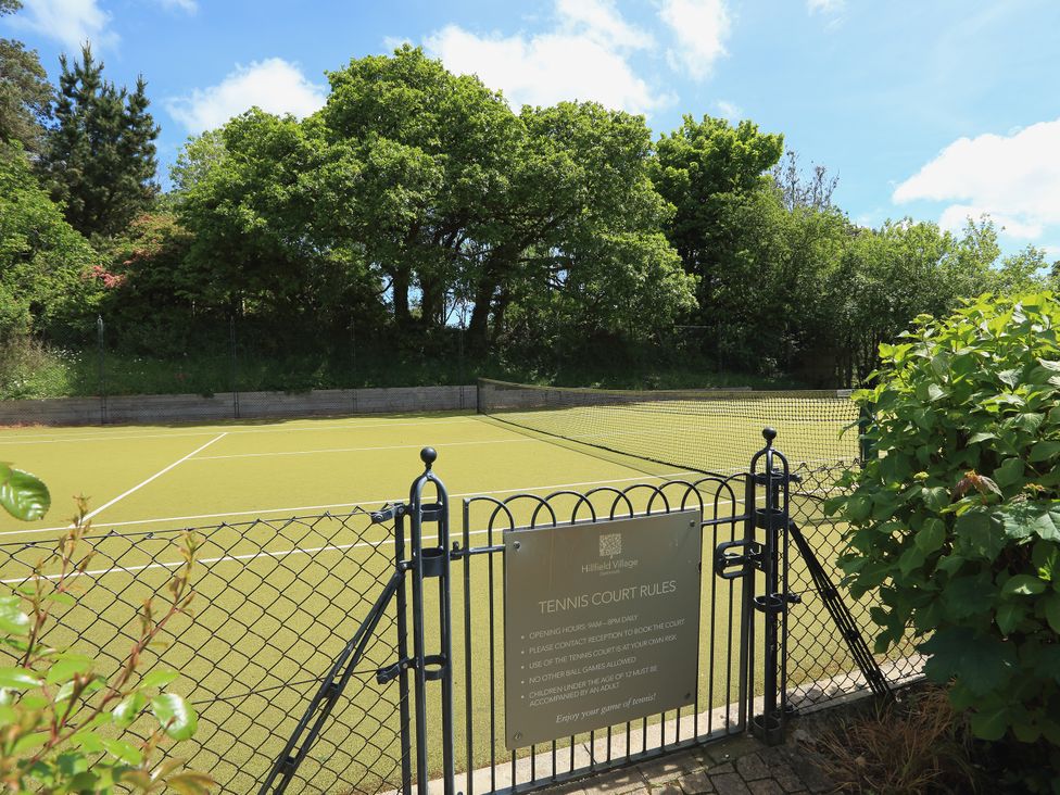 A tennis court with a rules sign at 2 The Manor House, Hillfield Village Dartmouth