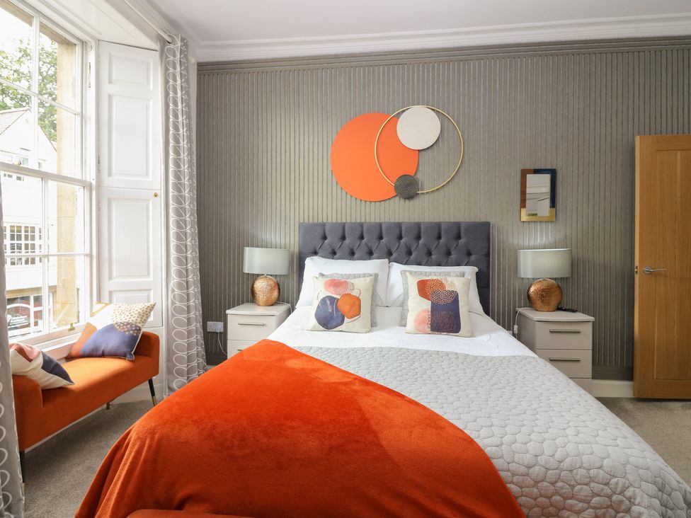 A bedroom with a bed and armchair at 2 Abbey Row in Kelso